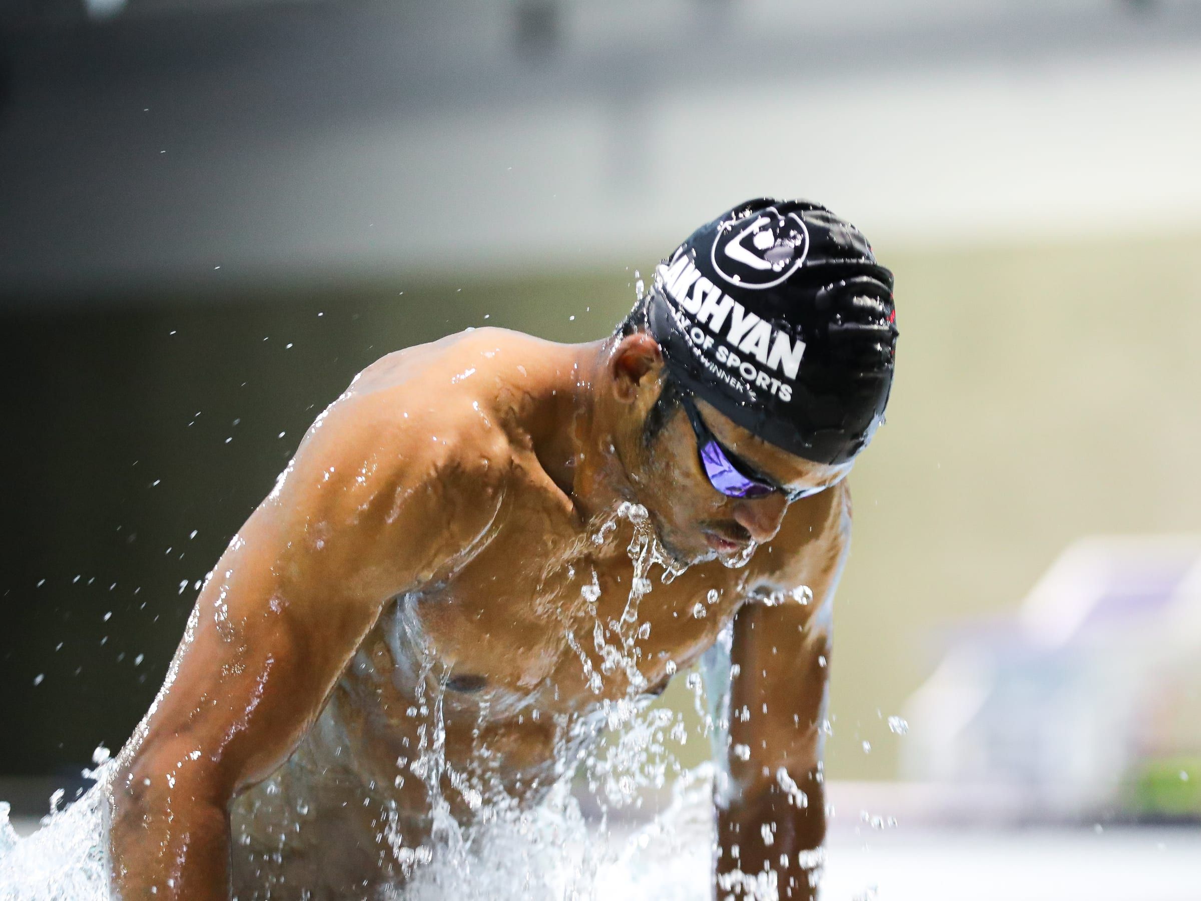 A swimmer surfacing mid-training, water spraying from the stroke